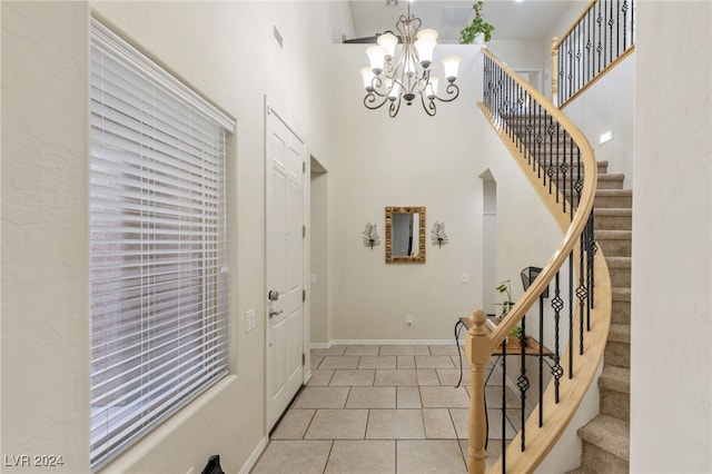 tiled entryway featuring a towering ceiling and a notable chandelier