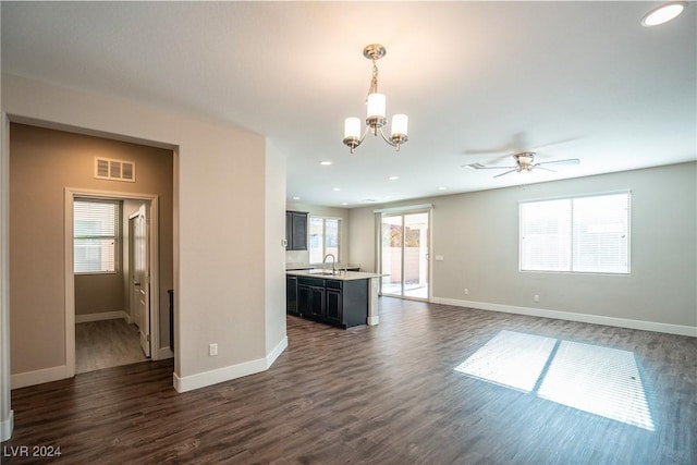 unfurnished living room featuring ceiling fan with notable chandelier, dark wood-type flooring, and sink