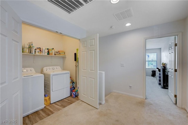 clothes washing area featuring light carpet and independent washer and dryer