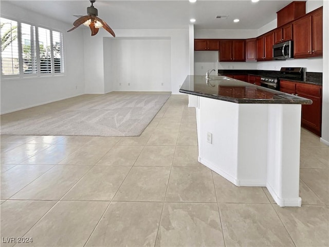 kitchen with ceiling fan, sink, stainless steel appliances, dark stone countertops, and light carpet