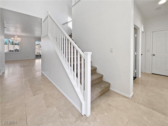 stairway with tile patterned floors and an inviting chandelier