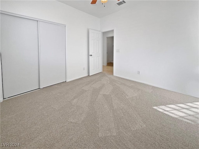 unfurnished bedroom with ceiling fan, light colored carpet, and a closet