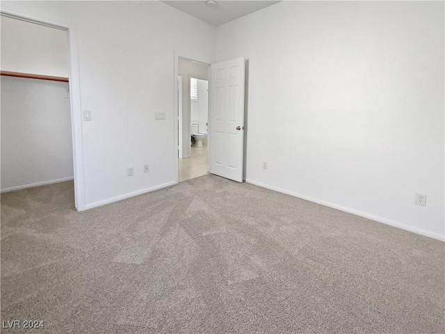 unfurnished bedroom with carpet flooring, a walk in closet, and a closet