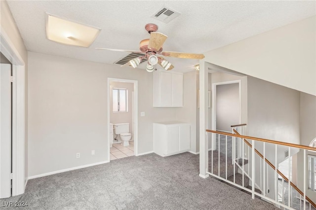 additional living space with ceiling fan, light colored carpet, and a textured ceiling