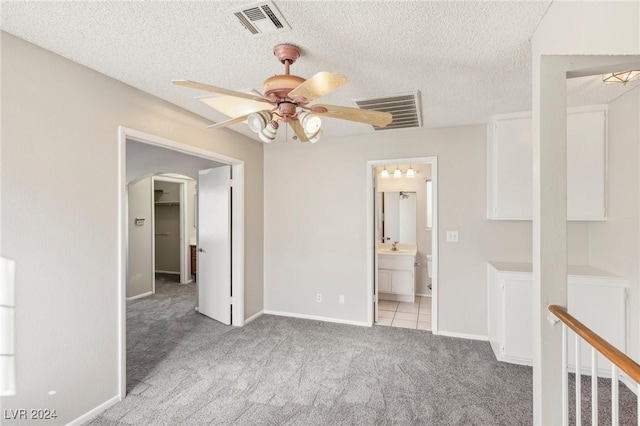 spare room featuring ceiling fan, light colored carpet, and a textured ceiling