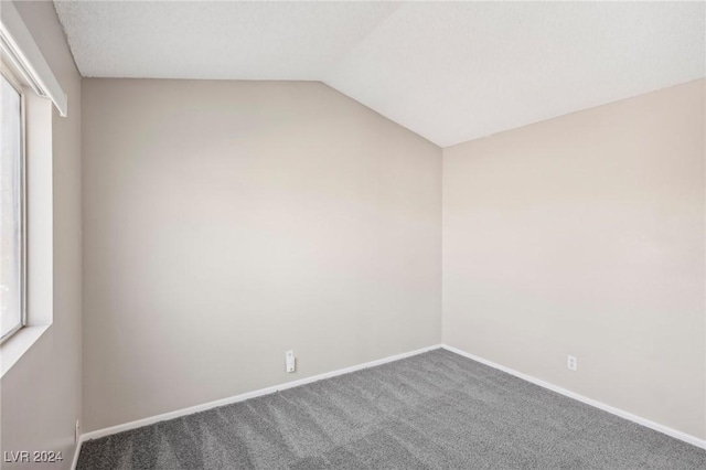 carpeted spare room featuring vaulted ceiling