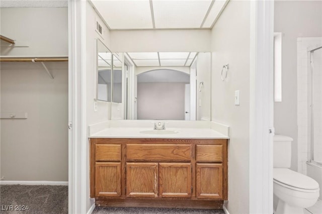 bathroom with walk in shower, vanity, and toilet