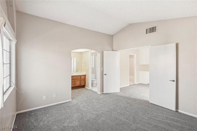 unfurnished bedroom with connected bathroom, light colored carpet, and vaulted ceiling