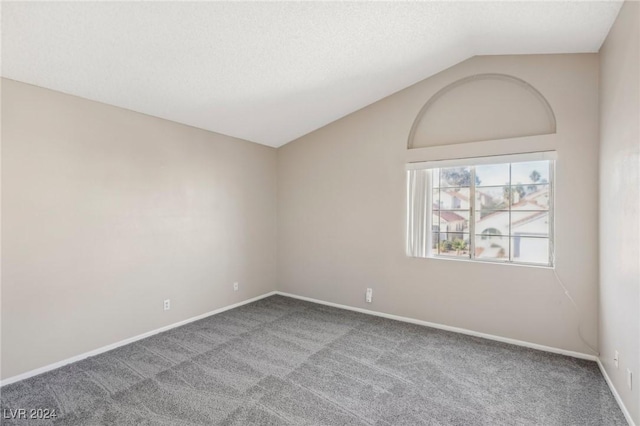 carpeted empty room with a textured ceiling and vaulted ceiling