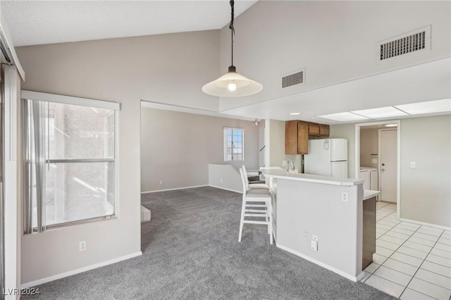 kitchen with independent washer and dryer, white fridge, pendant lighting, light colored carpet, and a breakfast bar area