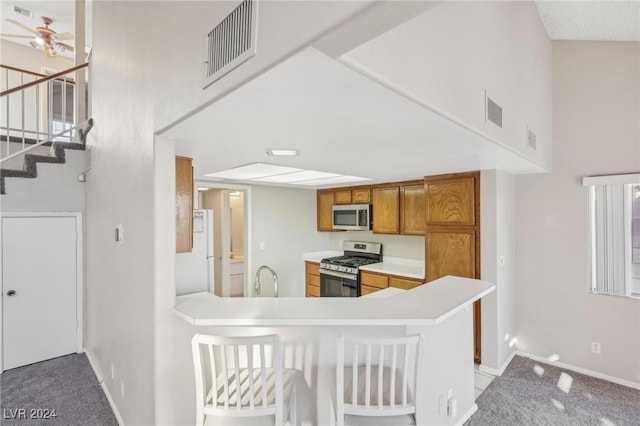 kitchen featuring ceiling fan, sink, kitchen peninsula, light carpet, and appliances with stainless steel finishes