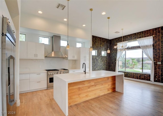 kitchen with white cabinetry, sink, wall chimney range hood, pendant lighting, and high quality appliances