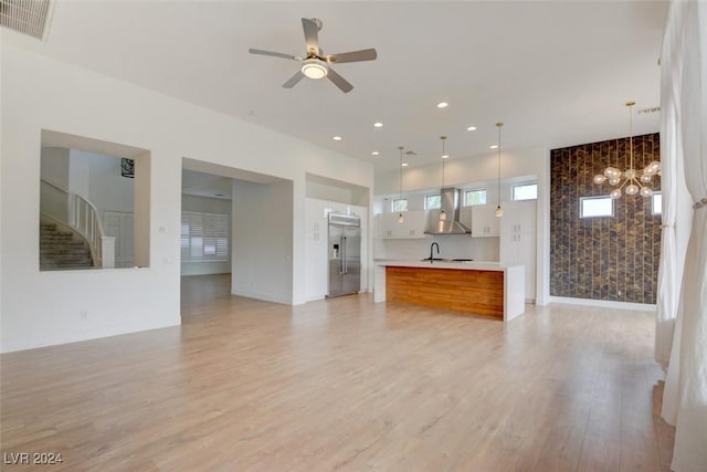 unfurnished living room featuring light wood-type flooring, ceiling fan, and sink