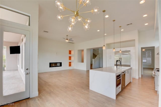 kitchen with decorative light fixtures, white cabinetry, a kitchen island with sink, and appliances with stainless steel finishes