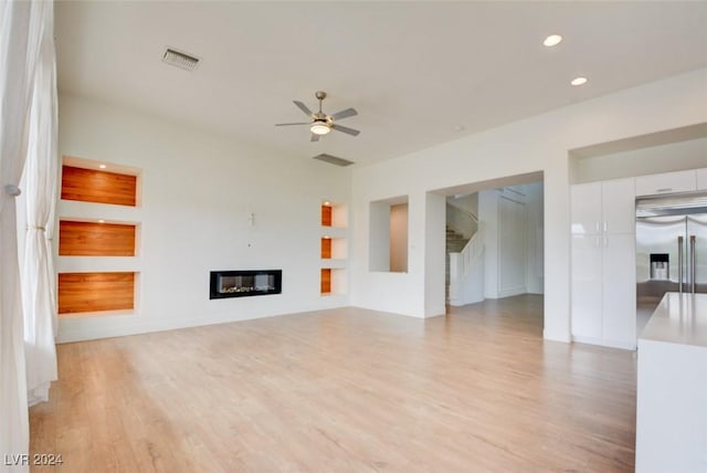 unfurnished living room with light wood-type flooring and ceiling fan