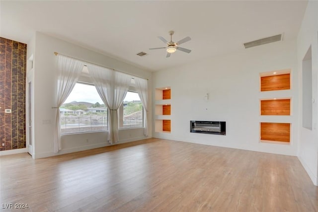 unfurnished living room with light wood-type flooring, heating unit, and ceiling fan