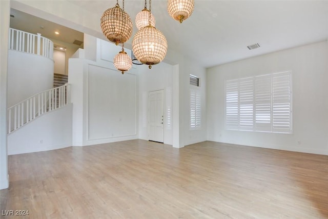 empty room featuring a chandelier and light hardwood / wood-style floors