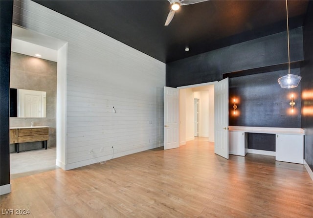 unfurnished living room with ceiling fan, light wood-type flooring, and a towering ceiling