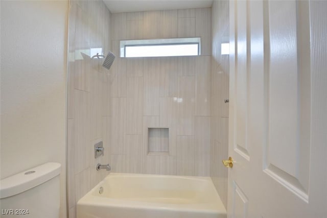 bathroom with tiled shower / bath combo and toilet