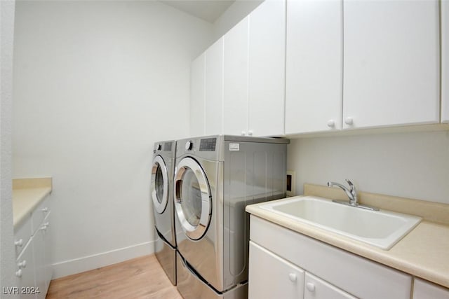 laundry room featuring cabinets, independent washer and dryer, light hardwood / wood-style floors, and sink