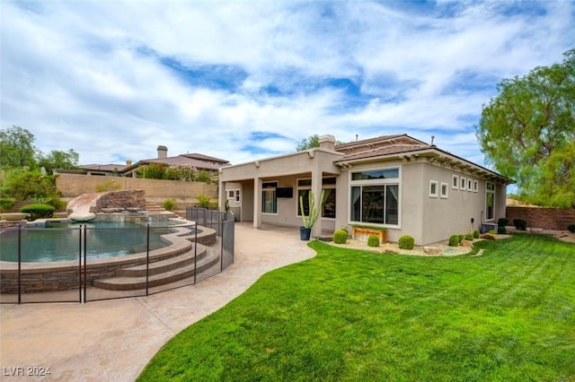 back of property with a fenced in pool, a patio area, and a lawn