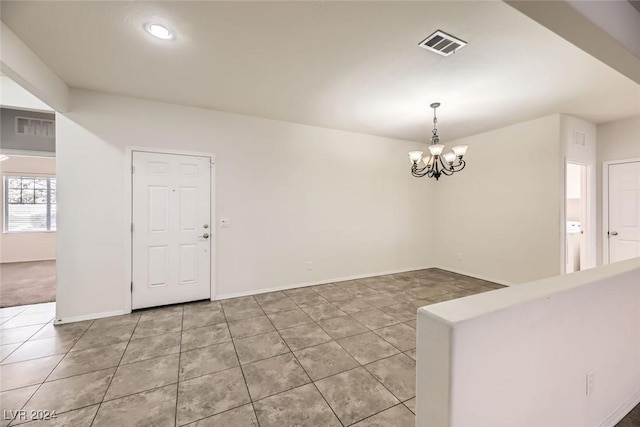 spare room with tile patterned floors and an inviting chandelier