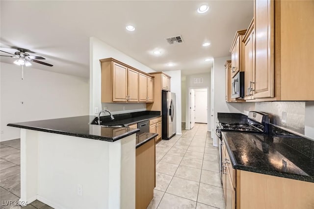 kitchen featuring ceiling fan, sink, stainless steel appliances, kitchen peninsula, and dark stone counters