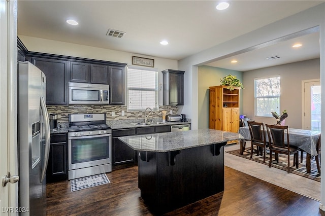 kitchen with dark hardwood / wood-style flooring, stainless steel appliances, a kitchen island, and sink