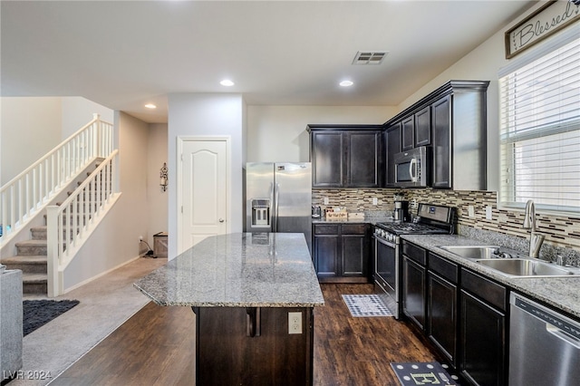 kitchen with sink, decorative backsplash, dark hardwood / wood-style floors, a kitchen island, and stainless steel appliances