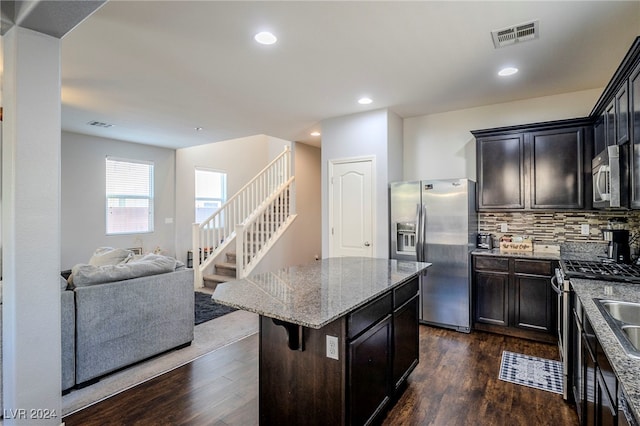 kitchen featuring a breakfast bar area, decorative backsplash, a kitchen island, dark hardwood / wood-style flooring, and stainless steel appliances