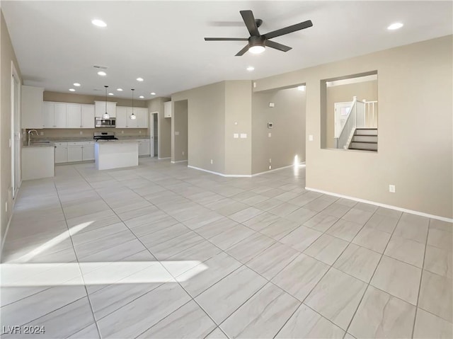 unfurnished living room featuring ceiling fan and sink