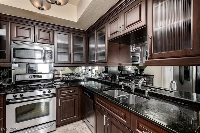 kitchen featuring dark stone countertops, dark brown cabinetry, sink, and appliances with stainless steel finishes