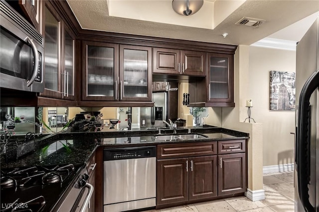 kitchen featuring dark stone counters, sink, stainless steel appliances, and dark brown cabinets