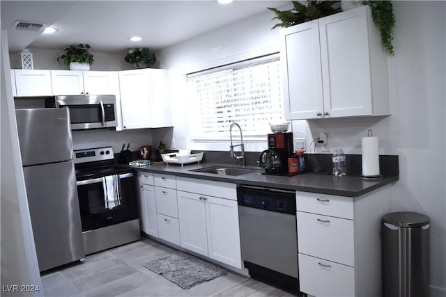 kitchen with appliances with stainless steel finishes, white cabinetry, and sink