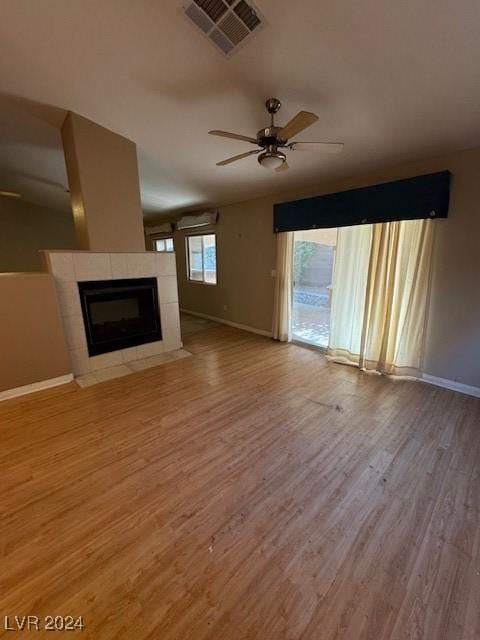 unfurnished living room featuring a tile fireplace, ceiling fan, and light hardwood / wood-style flooring