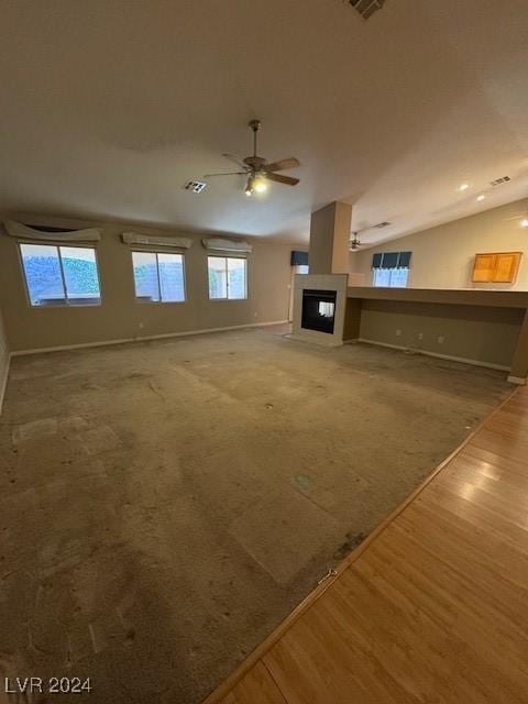 unfurnished living room with ceiling fan, wood-type flooring, a wealth of natural light, and lofted ceiling