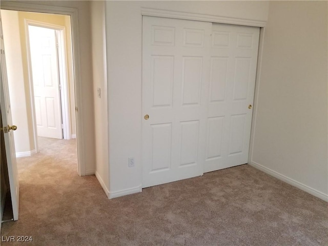 unfurnished bedroom featuring light carpet and a closet