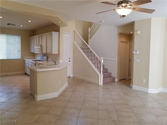 kitchen with white appliances, sink, ceiling fan, tile counters, and light tile patterned flooring