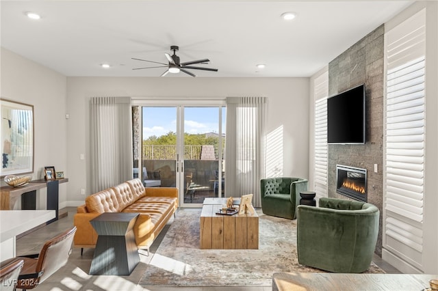 living room featuring ceiling fan and a large fireplace