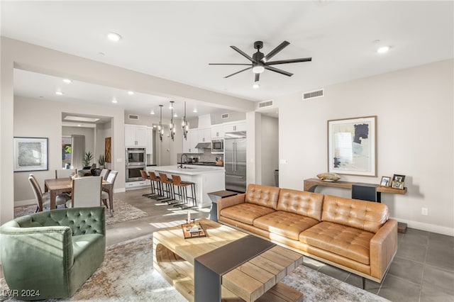 living room with ceiling fan, sink, and dark tile patterned floors