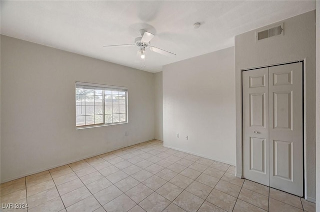 empty room with ceiling fan and light tile patterned floors