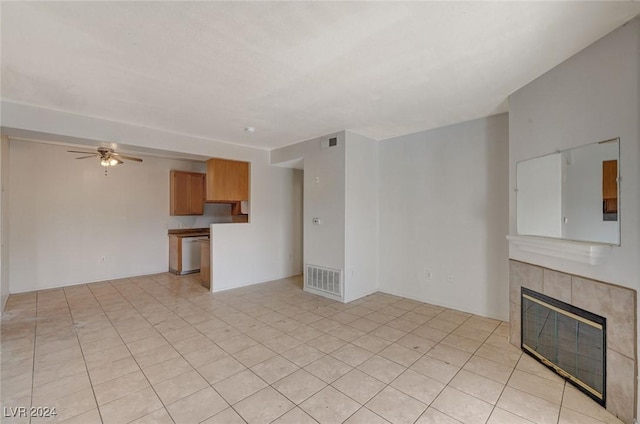 unfurnished living room with ceiling fan, a fireplace, and light tile patterned floors