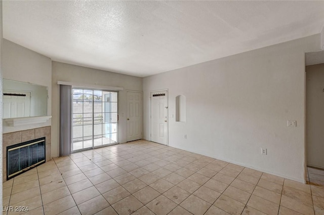 unfurnished living room with light tile patterned flooring, a textured ceiling, and a tile fireplace