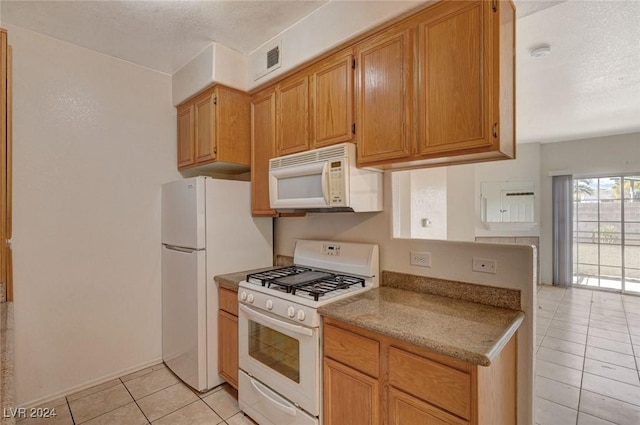 kitchen featuring light tile patterned floors, white appliances, and a textured ceiling