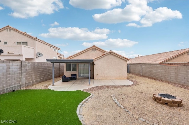 rear view of property featuring a yard, a patio, and an outdoor fire pit