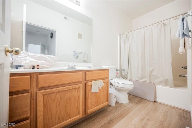 full bathroom featuring toilet, vanity, hardwood / wood-style flooring, and shower / tub combo with curtain