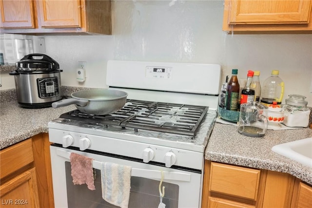 kitchen featuring light stone countertops and white range with gas cooktop