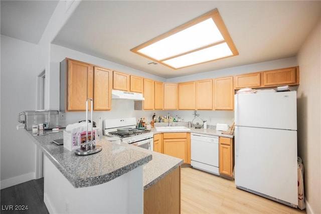 kitchen with kitchen peninsula, light brown cabinetry, white appliances, sink, and light hardwood / wood-style floors