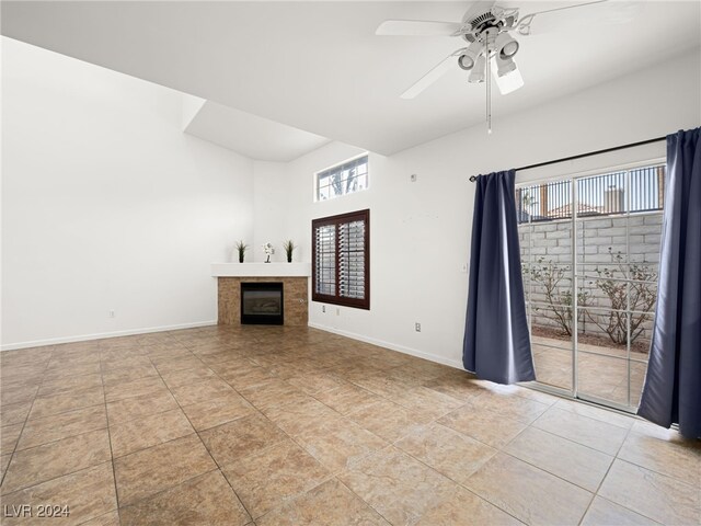 unfurnished living room featuring ceiling fan, light tile patterned floors, and a tiled fireplace