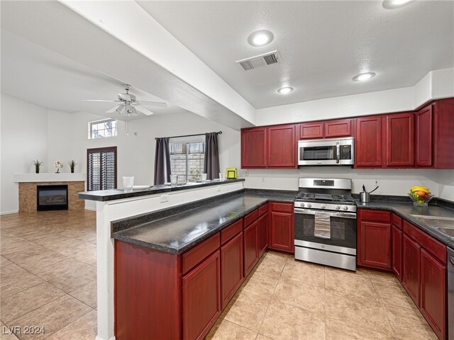 kitchen featuring ceiling fan, light tile patterned floors, a textured ceiling, kitchen peninsula, and stainless steel appliances